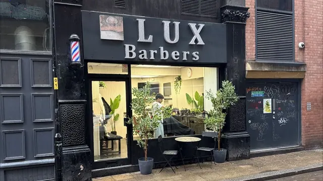The Lux Barbers shopfront, with olive trees and a barber's pole