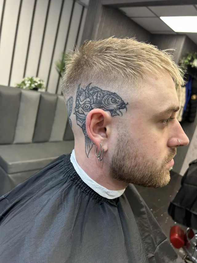 A textured crop with a skin fade, beside a head tattoo